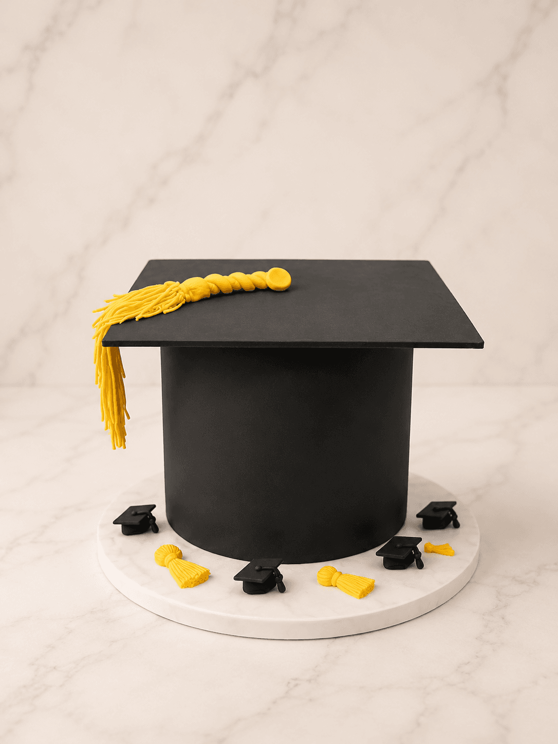 Black graduation cap cake with a yellow fondant tassel and mini mortarboard and tassel toppers