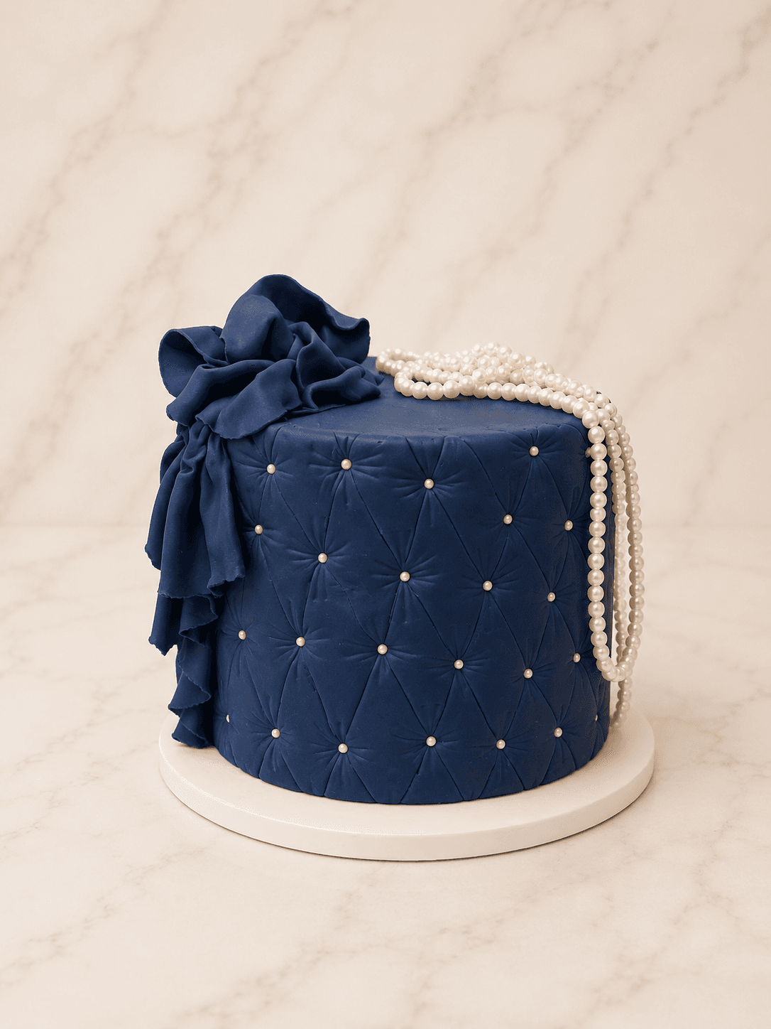 Navy fondant cake with a quilted diamond pattern, silver pearls, a draped bow, and cascading sugar pearls