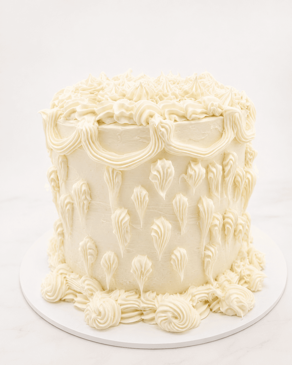 Tall white vintage Lambeth cake with piped buttercream swags, scrolls, and rosettes