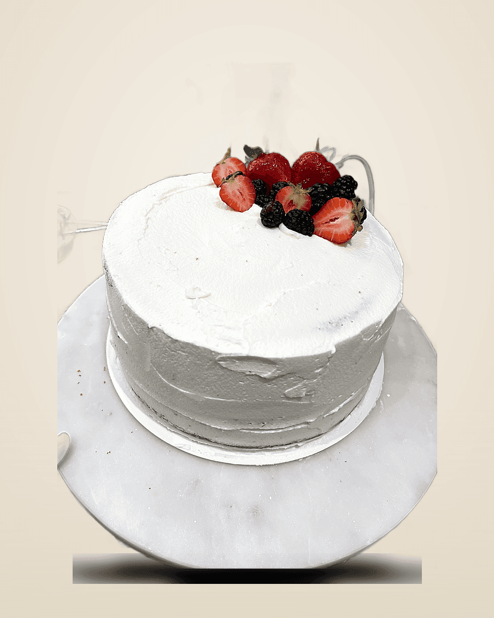 White buttercream cake topped with fresh strawberries and berries on a marble stand