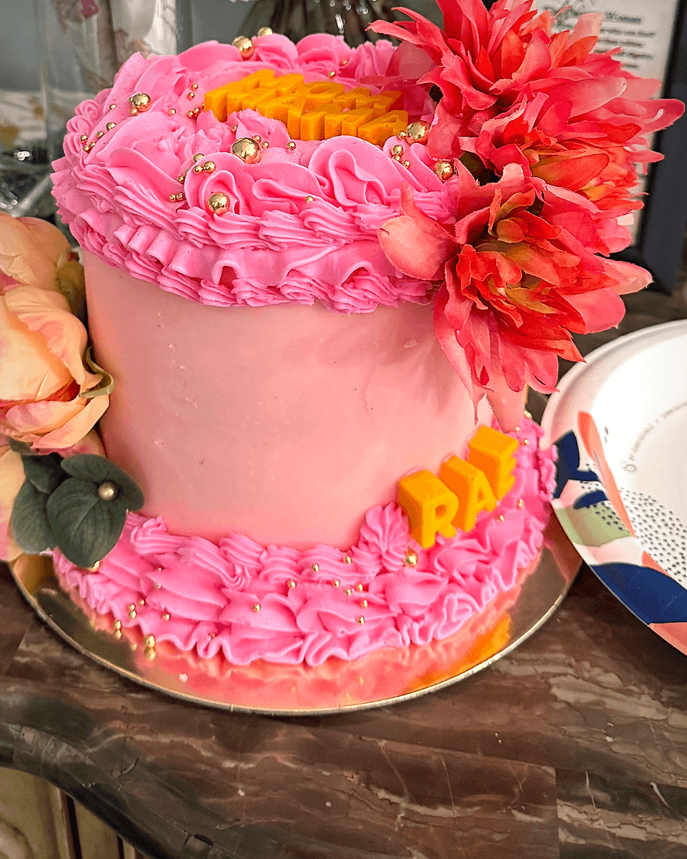 Pink ruffled buttercream cake crowned with bright fresh and sugar flowers
