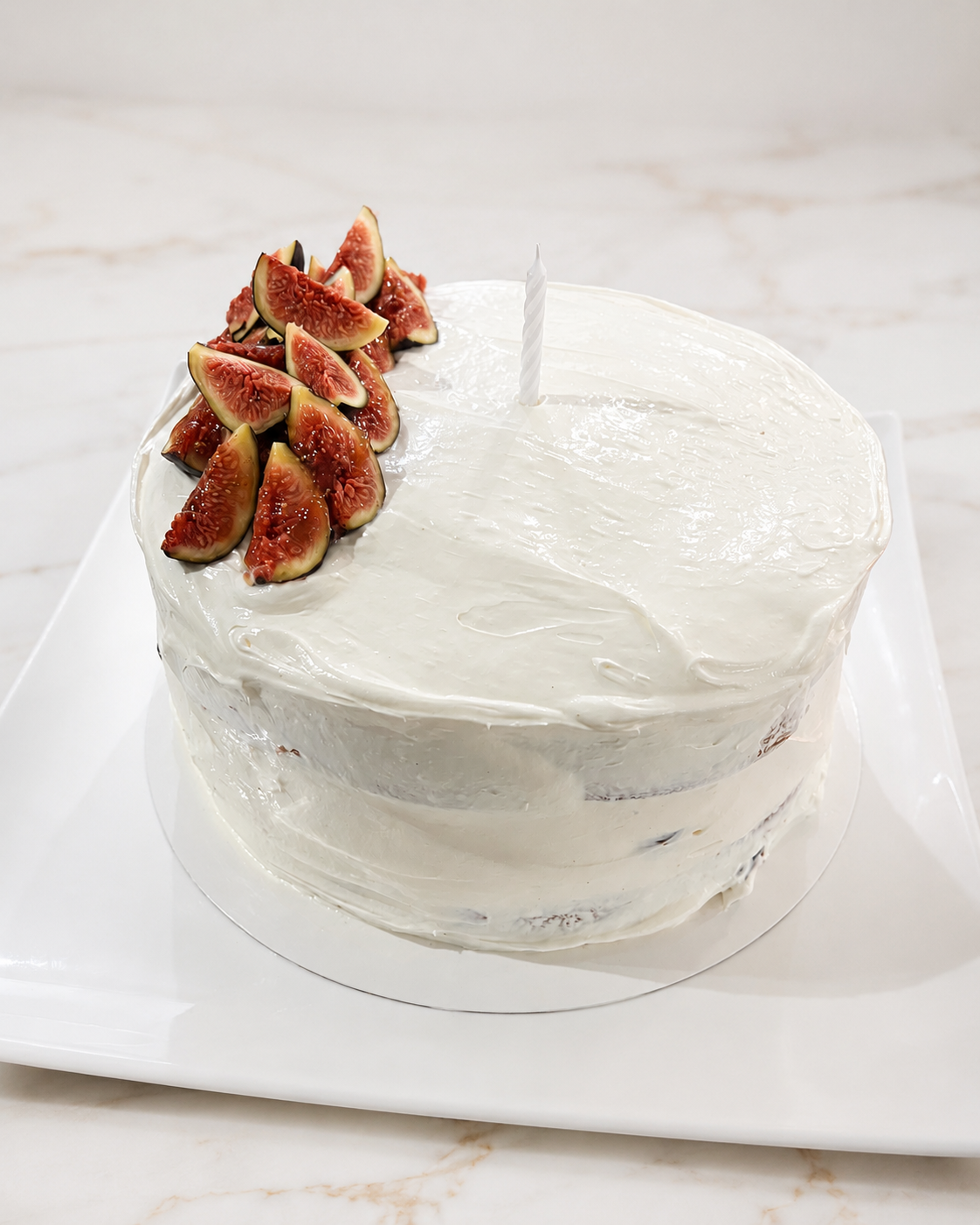 Semi-naked white cake topped with a cluster of fresh sliced figs