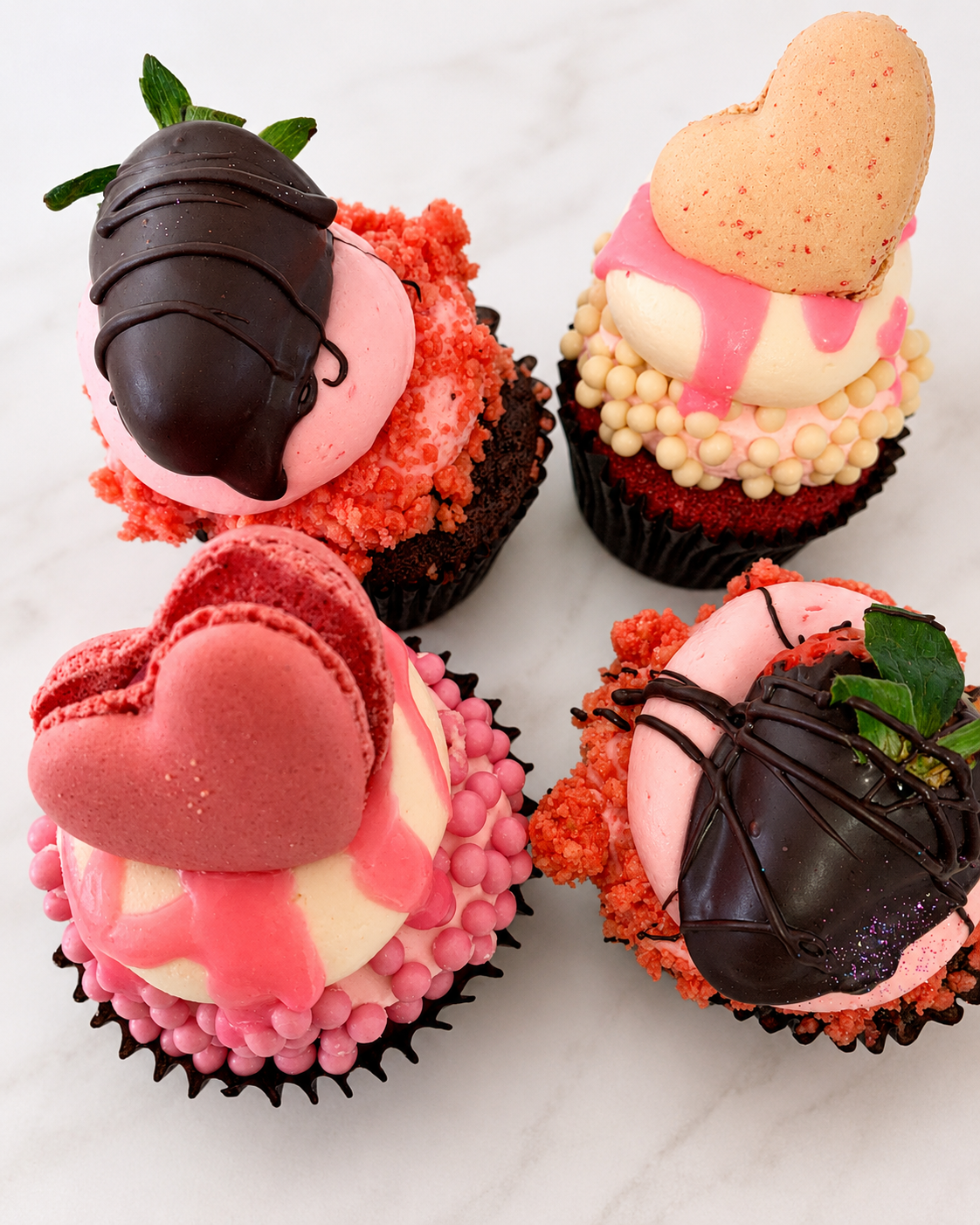 Box of decorated cupcakes with chocolate-dipped strawberries and heart cookies