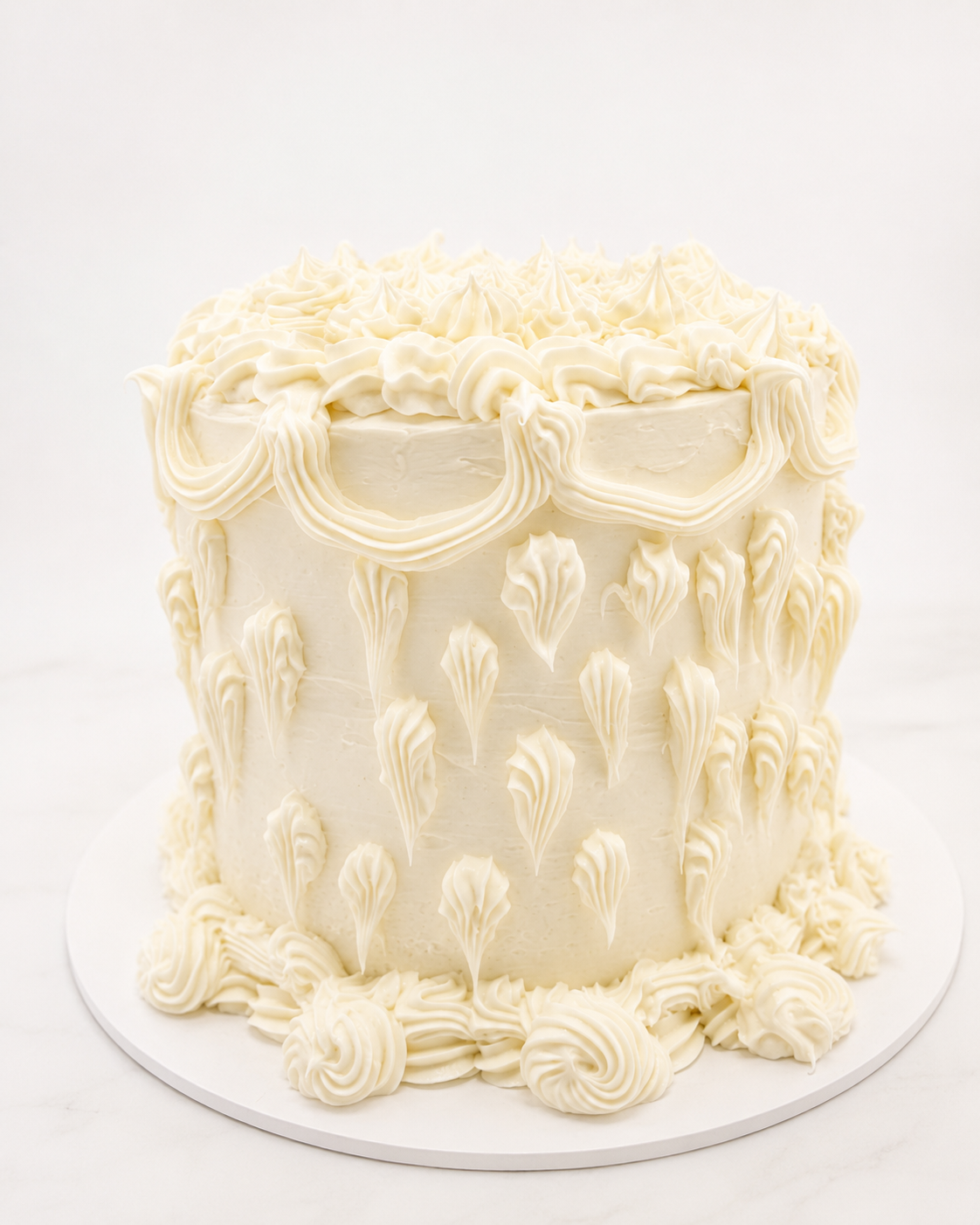 Tall white vintage Lambeth wedding cake with hand-piped buttercream swags and rosettes